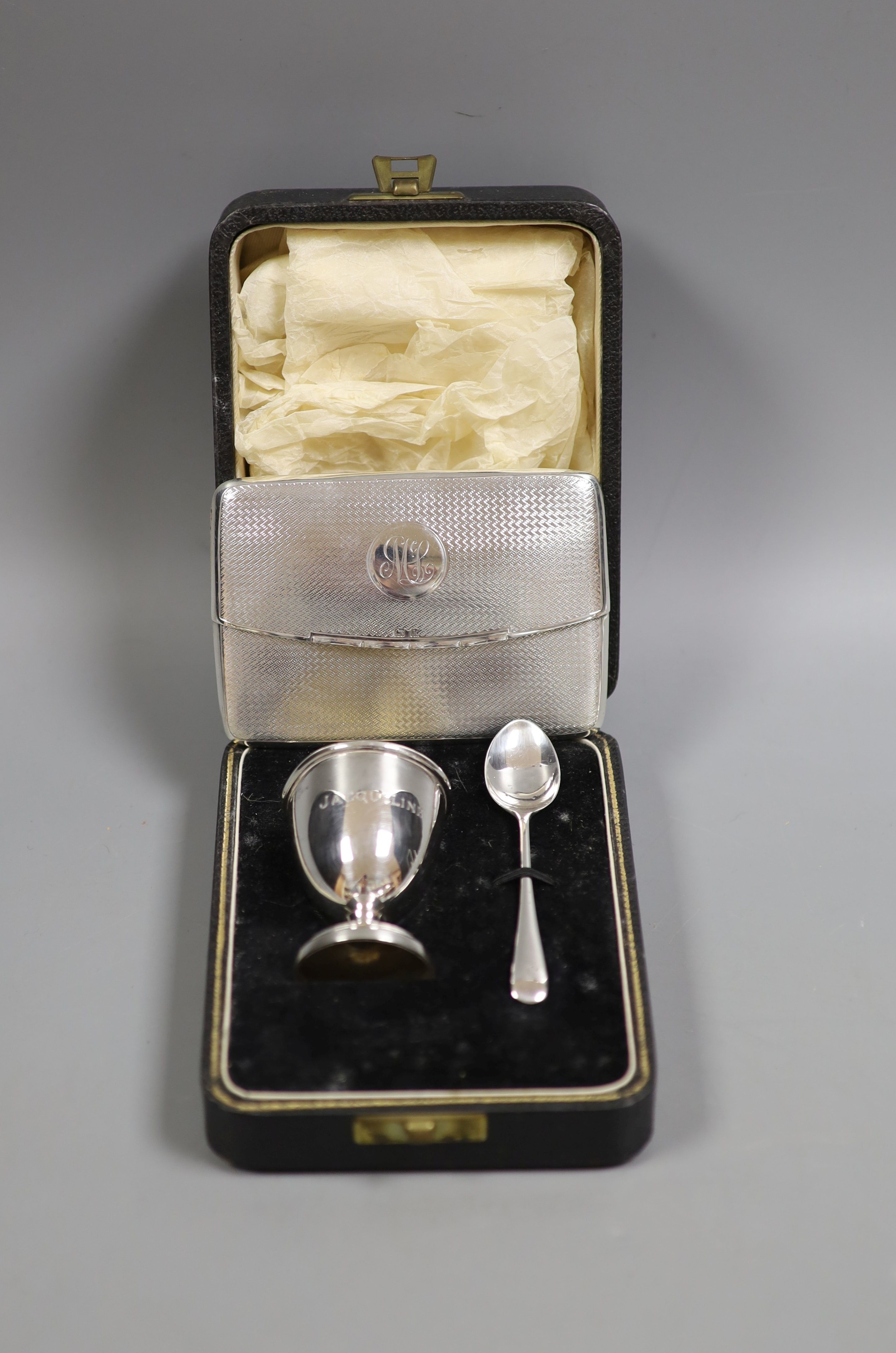 An Edwardian engine tuned silver 'envelope' card case, Birmingham, 1909, 10.4cm and a cased silver christening egg cup and spoon.